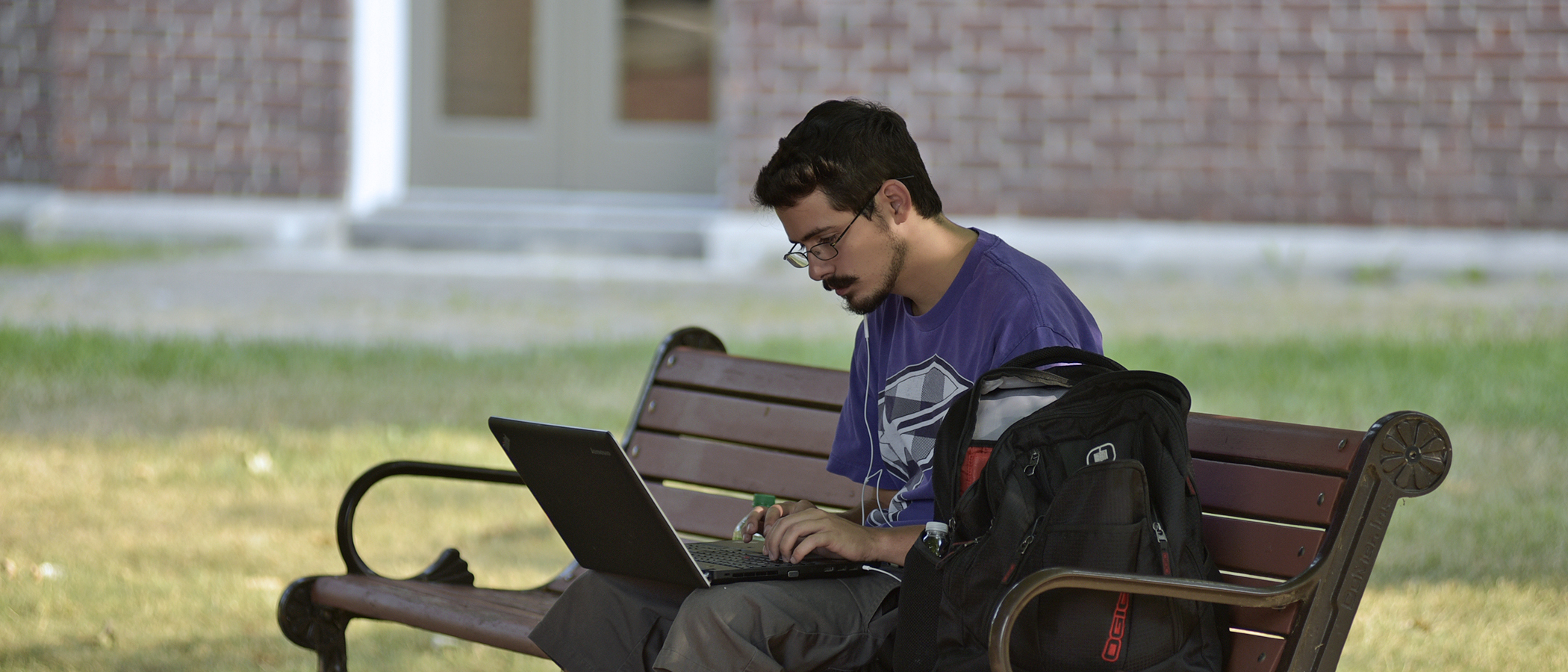 student working on laptop on an outdoor bench