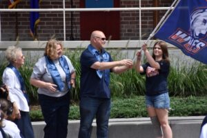 Peg Thorne Meisenhelder and Laura Piechota look on as Ed Piechota hands the university flag to incoming freshman and Legacy Student Jenna Piechota.