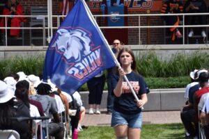 Incoming freshman and Legacy Student Jenna Piechota welcomes her classmates with the university flag.