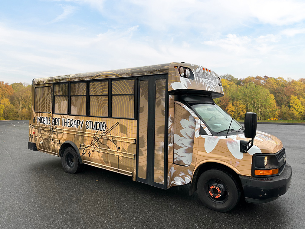 Alternate angle of the mobile art therapy bus, showing its design as a functional traveling art studio.