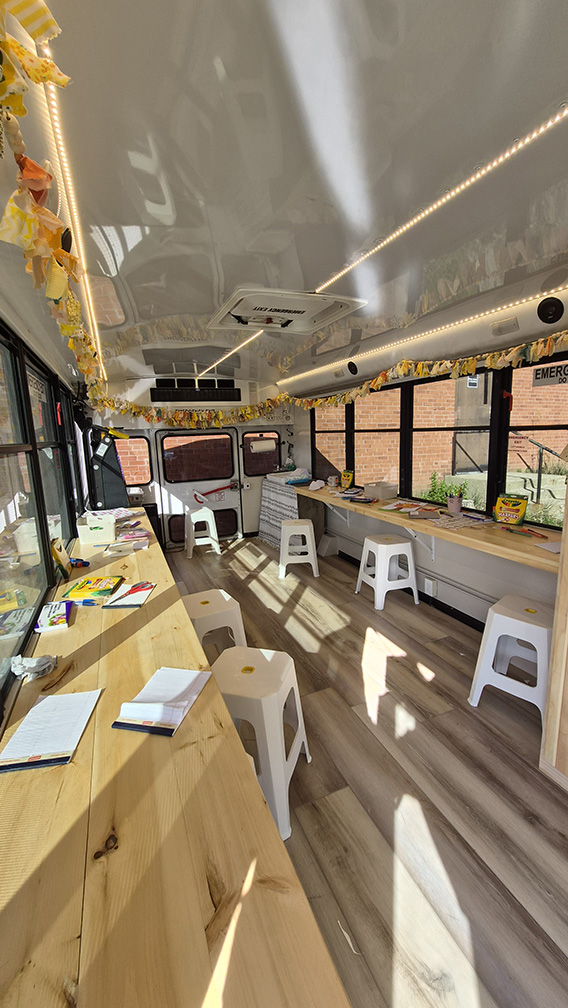 Interior of a mobile art therapy bus showing a clean, organized studio space with art materials and work surfaces.