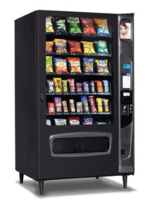 Glass-front snack vending machine stocked with a variety of chips, candy, crackers, and other packaged snacks.