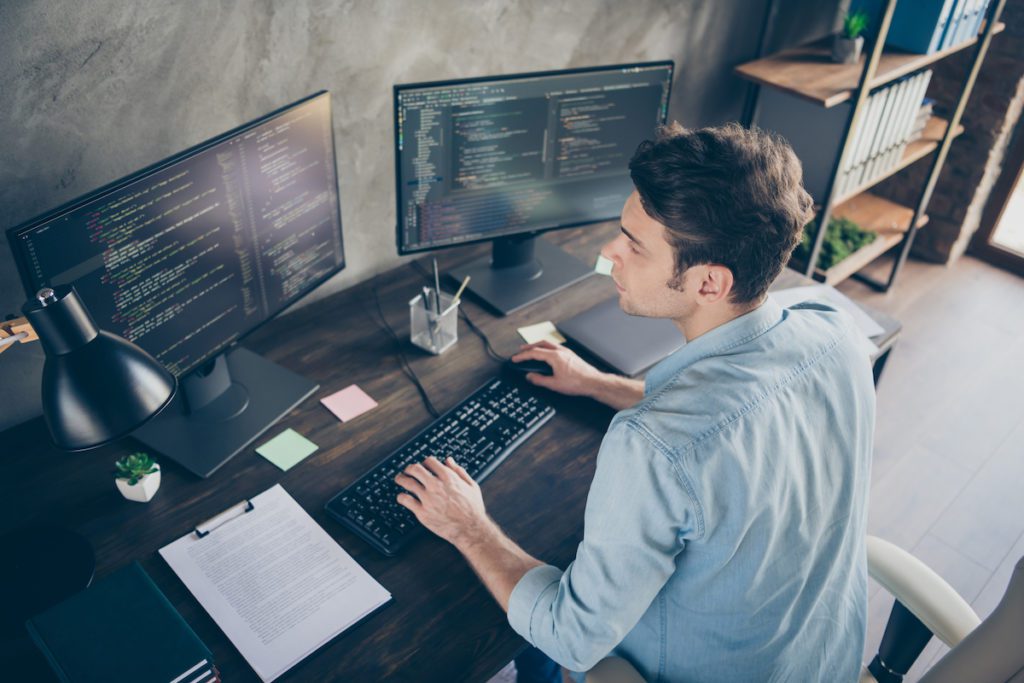 Man writing code on a desktop