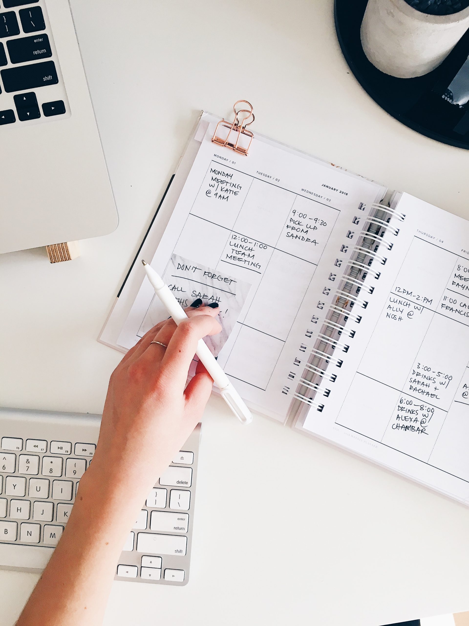 An agenda book, pen, and laptop on top of someone's desk.