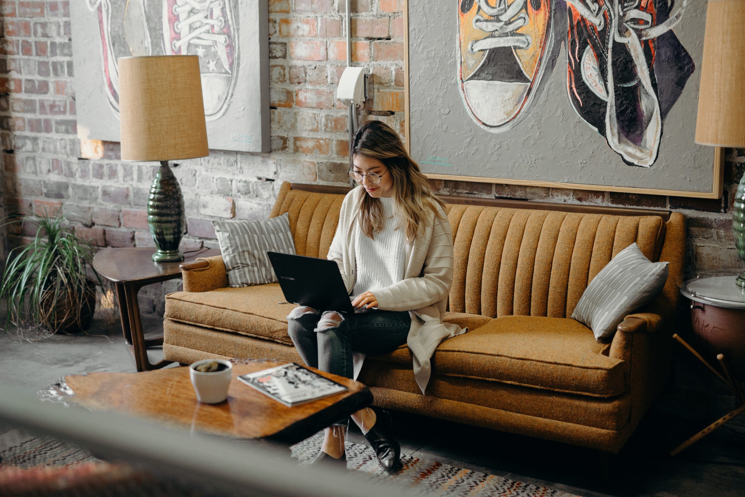 Woman sitting on a couch typing on a laptop