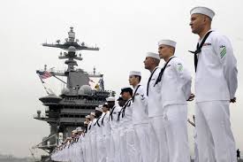 Row of sailors standing aboard an aircraft carrier