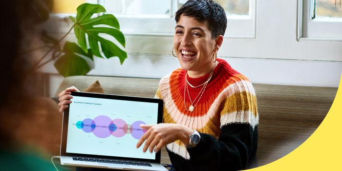 A women smiling, holding a laptop displaying a data graphic