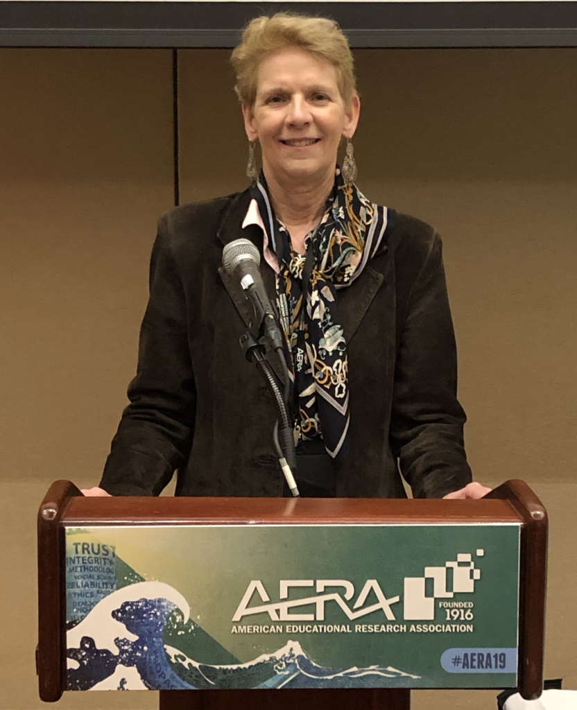 Dr. Marcia Delcourt standing in front of a podium at the AERA 2019 conference