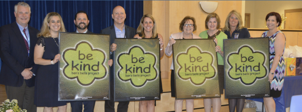 Group of people standing and holding Ben's Bells Project Be Kind poster boards