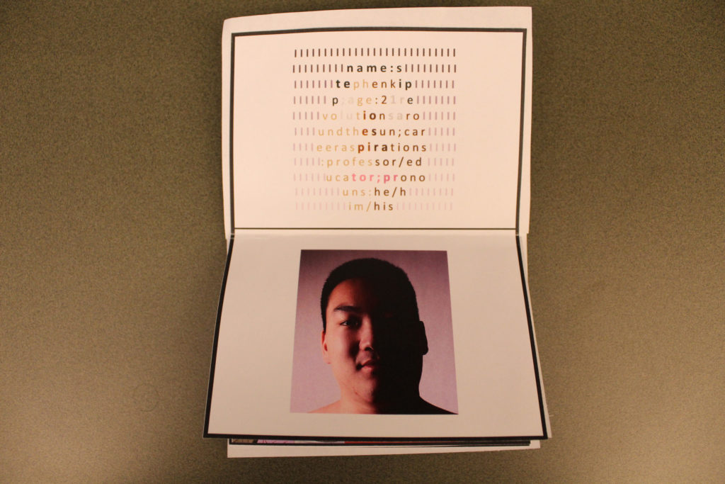 A folded piece of printer paper with black borders near the edges to create a passport. On the top is text that reads, "name: stephen kipp; age: 21 revolutions around the sun; career aspirations: professor/educator; pronouns: he/him/his." The text is wrapped in the shape of a face and is colored like a face. The face is surrounded by black lines that fade as they go down the page. On the bottom half is a picture of Stephen Kipp's face. They are male-presenting, and the right half of their face is dark.
