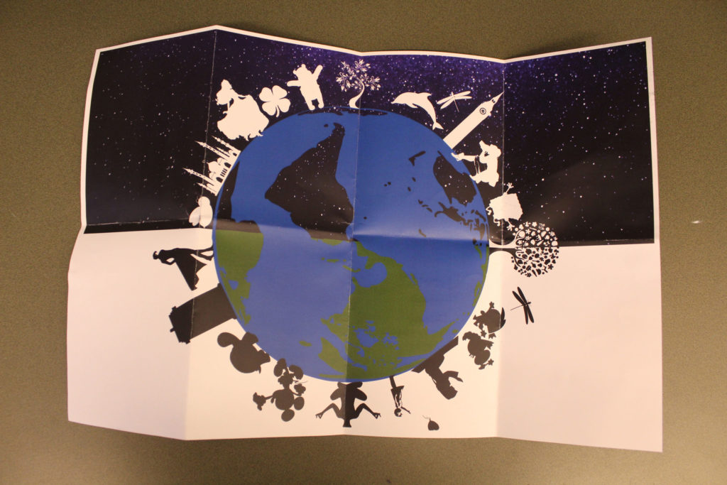 The silhouettes of various cartoon characters, monuments, animals, and plants stand around the globe, which is upside down. The background of the top half of the paper is a starry sky, and the bottom half is plain white.