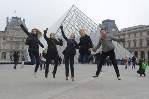 WCSU students, who are studying abroad in France, leap in the air for a photo in front of the Louvre.