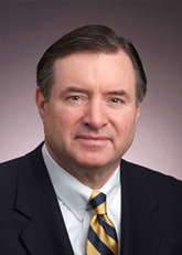 President Clark wearing a suit with golden and blue striped tie