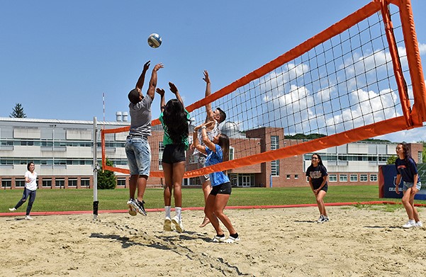 Students playing volleyball in the sand court