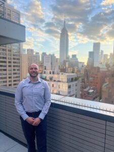 Managerial Accounting degree builds foundation for successful project accounting career WCSU alumnus Luke Holden WCSU alumnus Luke Holden Luke Holden stepped out onto the rooftop balcony of his Midtown Manhattan apartment near Grand Central Terminal recently, and pointed toward the sun as it set behind the Empire State Building. “WCSU gave me the tools to come down here and succeed,” he said. “I love living in New York City.” A little more than a decade earlier, as a student at Joel Barlow High School in Redding, Holden knew that after his June 2011 graduation, he wanted to go to WCSU. He enrolled as a Managerial Accounting major and settled into Litchfield Hall his freshman year, eager to begin his WCSU journey. Once on campus, he became actively involved in “the full college experience,” even joining the football team as a walk-on for two years. “My time with the team created close friendships that I still have to this day,” Holden said, sharing that he recently was a groomsman in a former teammate’s wedding. Reflecting on the first business class he took in the Westside Classroom Building, Holden said, “First, it’s daunting just to figure out how to get around the building; then it’s challenging to get the degree.” The challenge was mitigated by faculty members like Professor of Accounting Thomas Monks, Holden’s Ancell School of Business adviser. “He busted my chops a lot, but got me ready for the real world,” Holden said. “Another thing that separated me from other job candidates upon graduation was my ability to adapt, because at the Ancell School I learned accounting, fraud, business development and marketing as part of my Managerial Accounting degree.” Holden also took full advantage of WCSU’s Career Success Center, attending Career Fairs and making as many industry connections as he could. After graduation, he worked at a sales company in White Plains developing his business communication skills and building contacts in the construction industry in Manhattan. When he applied for an assistant project accountant position at AECOM Tishman, one of the leading construction management firms in the United States and the largest in New York City, he got the job. “The wide spectrum of business courses I took at WCSU helped my overall, broad business knowledge, and led to my hiring as a project assistant for the World Trade Center construction,” Holden said. Within two years, he was running the project in a senior accounting role responsible for cost reports, budgets and more. Now, six years after becoming a WCSU alumnus, he has joined Pavarini McGovern, another prominent New York-based construction management firm, as a project accountant. “I have coworkers who walk around in their Columbia and Cornell polo shirts, and I am just as proud to be from WCSU and the Ancell School of Business,” Holden said. “WCSU may not be an Ivy League school, but it prepares you in such a way that you have the ability to succeed. As a student, I worked two jobs and often took evening classes. I loved the flexibility and the ability to meet older students in night classes. You obtain the knowledge and the work ethic at WCSU, and apply it in the real world. “All of my experiences at WCSU were so great, and the quality of education that you get is so much better than what you pay for ,” Holden continued. “Many of my coworkers have debt, and I don’t. In addition to the cost-effectiveness of my degree, there are also the lifelong friendships and connections that I made.” Stopping for a moment to appreciate his view, Holden added, “I didn’t do this alone. It feels like there were a million people behind me at WCSU, helping me succeed.”