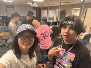 Students Chloe Wong and Brandon pose in the lab as Dr. Emilio Collar works with Evan and Ismael Shaker on a computer repair behind them.