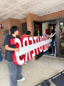 Students carefully carry in the vintage "Computers" sign that Dr. Collar acquired.